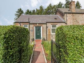 A stone cottage with a green door and hedge-lined pathway at Waterside Lodge near Annan