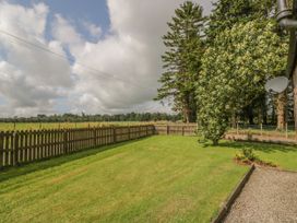 A fenced backyard with grass trees and a satellite dish on a building at Waterside Lodge near Annan