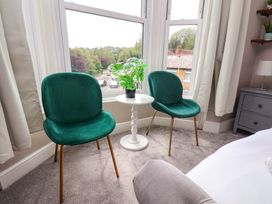 A sitting room with green chairs and a small table at The Corner House in Scarborough