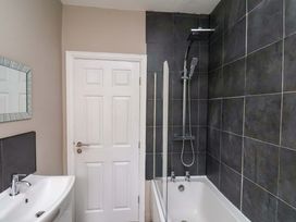A bathroom with a bath, shower, and mirror at The Corner House in Scarborough