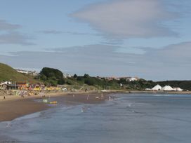 A beach with colorful beach huts and people at Scarborough