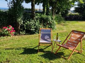 A garden with deck chairs and a table at Driftwood in Dartmouth
