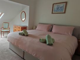 A bedroom with a bed, dresser, chair, and mirror at Sally End in Ravenstonedale near Kirkby Stephen