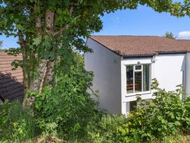 An exterior view of a white house with a brown tiled roof and surrounding green trees and bushes at 37 Tamar in St Ann's Chapel near Callington