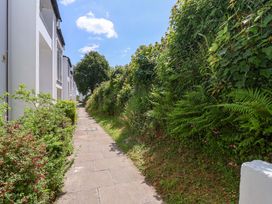 A paved walkway bordered by buildings on one side and dense greenery on the other at 37 Tamar in St Ann's Chapel near Callington