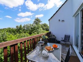 A balcony with a glass table and chairs overlooking greenery at 37 Tamar St Ann's Chapel near Callington