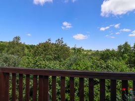 A wooden balcony railing overlooking dense green trees and bushes with a clear blue sky at 37 Tamar in St Ann's Chapel near Callington