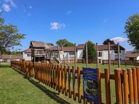 A fenced playground with a wooden play structure and residential buildings in the background at 37 Tamar in St Ann's Chapel near Callington
