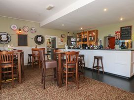 An interior of a pub with wooden tables and chairs a white bar counter with stools darts on the wall and a specials board at 37 Tamar in St Ann's Chapel near Callington