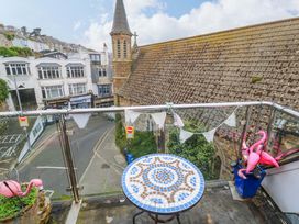 A balcony with a table and flamingo decorations at Harbour View in St Ives
