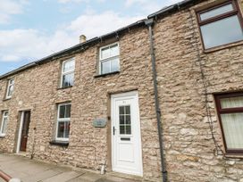 An exterior view of a stone cottage with front door and windows at Fettlers Cottage, 51 High Street Kirkby Stephen