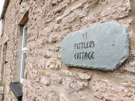 A stone wall with a slate sign displaying the name of the property at Fettlers Cottage, 51 High Street