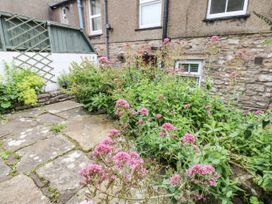A garden with flowers and a stone path at Fettlers Cottage, 51 High Street, Kirkby Stephen