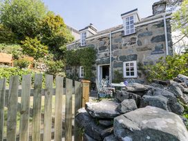 A stone cottage with a small fenced garden and outdoor table and chairs at Pen Y Bryn Bach in Harlech