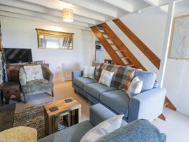 A living room with a blue sofa an armchair a wooden coffee table a television and wooden stairs at Pen Y Bryn Bach in Harlech