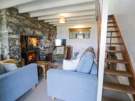 A living room with sofas a stone fireplace a wood burning stove a wooden staircase and a television at Pen Y Bryn Bach in Harlech