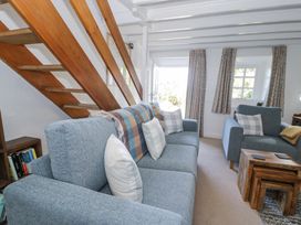 A living room with blue sofas wooden stairs and a window with curtains at Pen Y Bryn Bach in Harlech