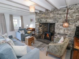A living room with stone fireplace and wood stove surrounded by armchairs and a sofa at Pen Y Bryn Bach in Harlech