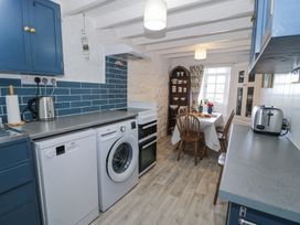 A kitchen with a washing machine dishwasher dining table wooden chairs and a display cabinet at Pen Y Bryn Bach in Harlech