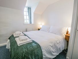 A bedroom with a double bed covered in white bedding and green blanket with folded towels on the bed at Pen Y Bryn Bach in Harlech