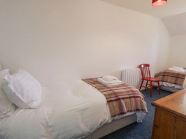 A bedroom with two single beds with blankets and towels a red wooden chair and a wooden dresser at Pen Y Bryn Bach in Harlech