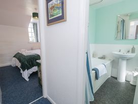 A view of a bedroom with a bed and a bathroom with a bathtub and sink at Pen Y Bryn Bach in Harlech