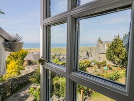 View through a white window frame showing rooftops, gardens, trees, and the sea in the background at Pen Y Bryn Bach in Harlech