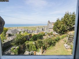 A view of a garden with greenery houses and a castle in the background near the coast at Pen Y Bryn Bach in Harlech