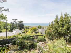 A garden with a wooden gate overlooking houses and the sea at Pen Y Bryn Bach in Harlech