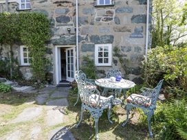 A garden area with a round metal table and four chairs outside a stone house at Pen Y Bryn Bach in Harlech