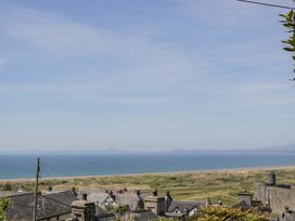 A coastal view with rooftops in the foreground grassy dunes and sea in the background at Pen Y Bryn Bach in Harlech