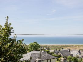 A coastal view with rooftops of houses in the foreground trees and the sea in the background at Pen Y Bryn Bach in Harlech