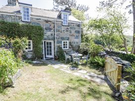 A stone house with a small garden patio table and chairs surrounded by greenery at Pen Y Bryn Bach in Harlech