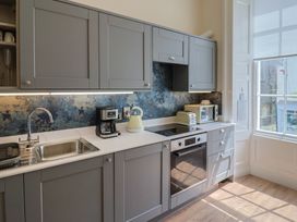 A kitchen with cabinets, sink, coffee maker, and oven at FLAT 1 53a Broad Street (1 Bedroom Sleeping 2) Lyme Regis