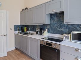 A kitchen with cabinets, sink, kettle, coffee maker, and oven at FLAT 1 53a Broad Street (1 Bedroom Sleeping 2) Lyme Regis