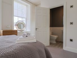 A bedroom with a bed and a door leading to a bathroom at FLAT 1 53a Broad Street (1 Bedroom Sleeping 2) Lyme Regis