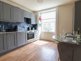 A kitchen with cabinets, sink, and dining table at FLAT 2 53a Broad Street (1 Bedroom Sleeping2) Lyme Regis