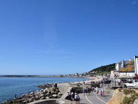 A coastal scene with people walking along the beach at Saltwind in Lyme Regis