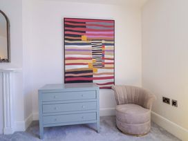 A living room with a decorative artwork and a chest of drawers at Pebble Cove in Lyme Regis