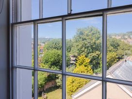 A window with a view of trees and a garden at Pebble Cove in Lyme Regis