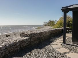 A view of the sea and shoreline with stones and a pathway at Driftwood Cottage in Ulverston