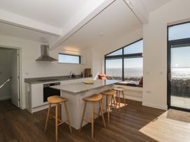 A kitchen with an island counter and bar stools at Driftwood Cottage in Ulverston