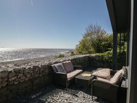 An outdoor seating area with chairs and a table overlooking the sea at Driftwood Cottage Ulverston