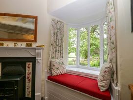 A sitting room with a window seat and mirror at Hollens Cottage in Grasmere
