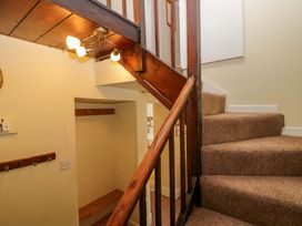 A staircase with a handrail and wall hooks at Hollens Cottage in Grasmere