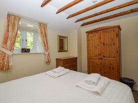 A bedroom with a bed and wooden furniture at Hollens Cottage in Grasmere
