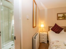 A bedroom with a bed and a shower in the corner at Hollens Cottage in Grasmere