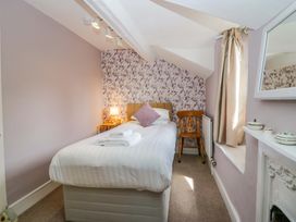A bedroom with a single bed, chair, and lamp at Hollens Cottage in Grasmere