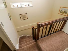 A staircase with wood railing and framed pictures at Hollens Cottage in Grasmere