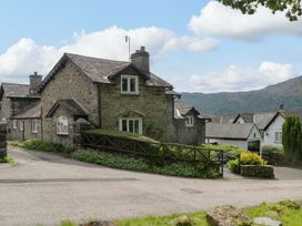 A stone cottage with a fence and driveway at Hollens Cottage in Grasmere